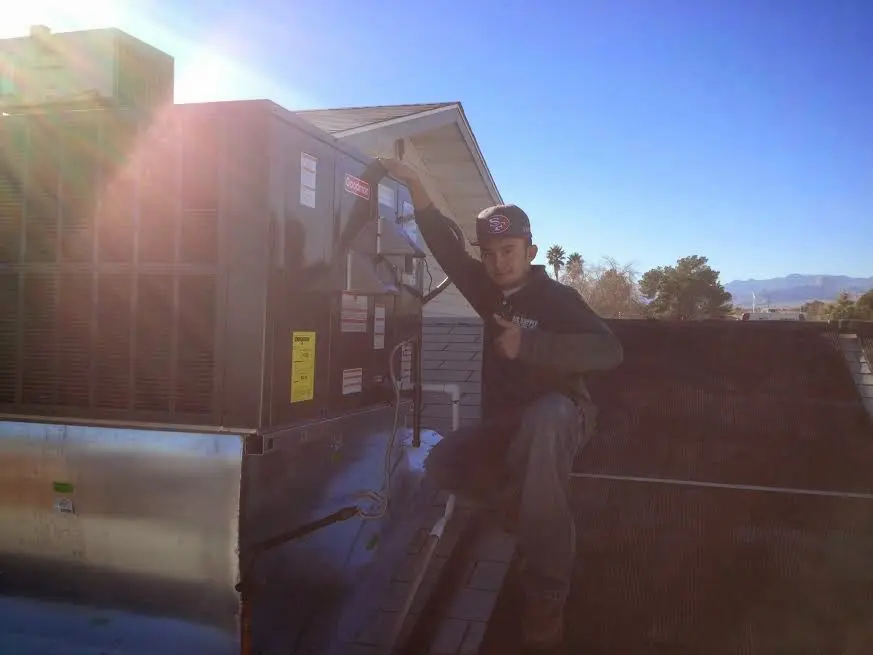 HVAC technician performing Air Duct Cleaning on a rooftop unit in Americus
